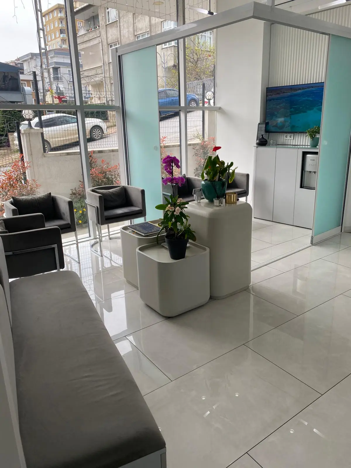 Bright patient waiting lounge at EsteQuality Dental with grey seating, large windows, and contemporary decor.
