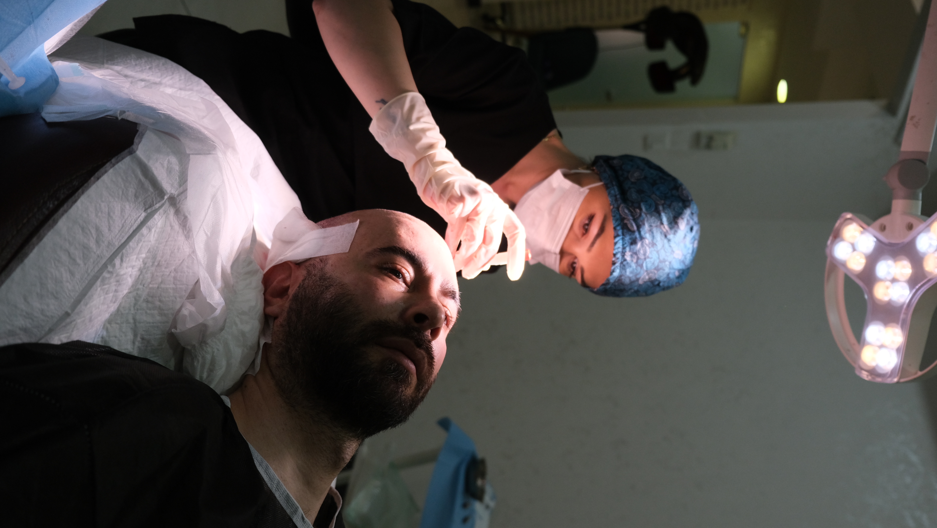 A medical team member assessing the treatment area during the hair transplant procedure